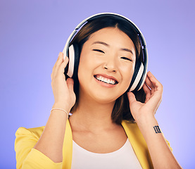 Image showing Headphones, music and happy Asian woman in studio listening to audio, streaming song and radio. Entertainment, subscription and female person relax with earphones for album on purple background