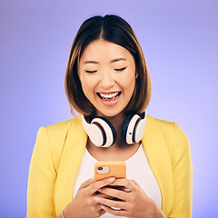 Image showing Headphones, phone and happy Asian woman in studio smile for social media, internet meme and chat. Texting, smile and female person on smartphone listen to audio, song and track on purple background