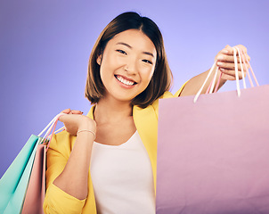 Image showing Shopping bag, portrait and woman offer for fashion discount, deal or sale on studio, purple background. Giving, gift or competition of young customer, model or asian person, winning and retail prize