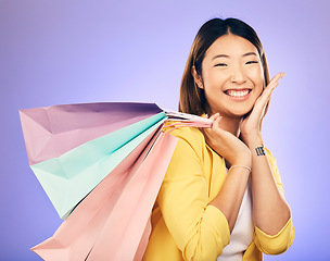 Image showing Happy, portrait and woman with shopping bag, retail and commerce with fashion sale on purple background. Discount at boutique shop, Asian female customer and market with store promotion in studio