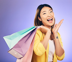 Image showing Shopping bag, wow portrait and woman of beauty discount, retail announcement or sale on purple studio background. Cosmetics, excited face and young customer or asian person for prize, gift or winning