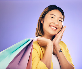 Image showing Smile, portrait and woman with shopping bag, retail and commerce with fashion sale on purple background. Discount at boutique shop, Asian female customer and market with store promotion in studio