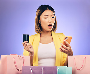 Image showing Credit card, phone and woman stress, surprise or shocked for online shopping scam, news or fintech payment problem. Wow, retail bag and asian person for e commerce mistake on purple studio background