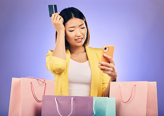 Image showing Woman, confused and credit card, phone and online shopping scam, news or fintech payment problem. Stress, retail bag and sad asian person in e commerce mistake on mobile and purple studio background