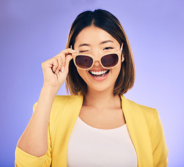 Image showing Happy, portrait of asian woman wink with glasses in studio, purple background and fashion. Face, female model and blink emoji with sunglasses for secret, fun personality and gen z girl in good mood