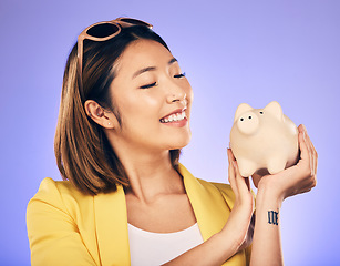 Image showing Piggy bank, finance and woman thinking of savings, investment and happy for money growth goals. Young asian person for financial management, money safe or banking security on studio purple background