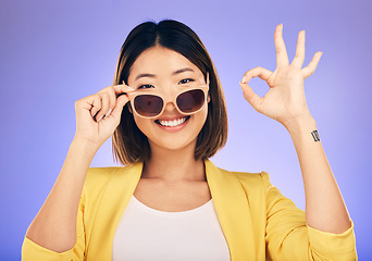 Image showing Happy asian woman, portrait and sunglasses, OK sign or fashion accessory against a purple studio background. Female person or model smile with okay gesture in satisfaction for perfect summer style