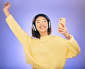 Image showing Dance, music and Asian woman with phone in studio for streaming, subscription and radio. Relax, headphones and happy female person on smartphone listen to audio, song and track on purple background