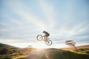 Image showing Fitness, cycling and person with bicycle jump for extreme sports and energy on blur mockup space . Action, bike and cyclist athlete in the countryside with speed, trick and skill, adventure or power