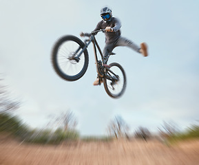 Image showing Mountain, bicycle jump and athlete cycling on a bike for extreme sports competition stunt or training in nature. Skill, contest and person workout or action on sky or air trick for fitness with blur