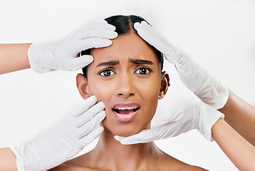 Image showing Plastic surgery, scared and face of woman with hands of prp doctors on white background in studio. Beauty, portrait and indian female model with fear, stress and anxiety for facial aesthetic change