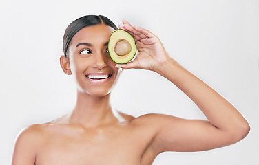 Image showing Avocado, eye skincare and happy woman isolated on a white background for healthy facial and cosmetics ideas. Indian person or beauty model thinking of green, vegan or dermatology product in studio