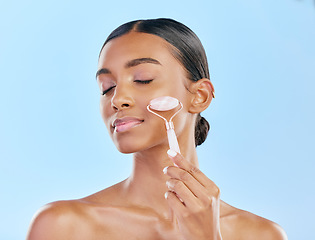 Image showing Facial massage, woman and roller, beauty and skincare, natural cosmetics and tools isolated on blue background. Rose quartz, crystal and skin glow, Indian female model with dermatology and antiaging