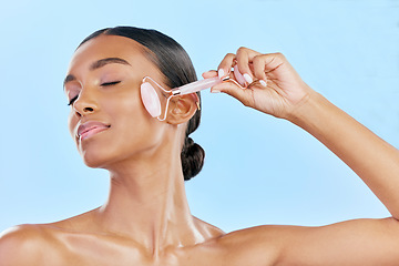 Image showing Facial massage, woman and roller, natural beauty and skincare, cosmetics and tools isolated on blue background. Rose quartz, crystal and skin glow, Indian female model with dermatology and antiaging