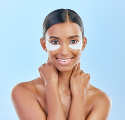 Image showing Eye patch, portrait and beauty of a woman with natural skin glow on a blue background. Dermatology, collagen face mask and cosmetics of Indian female model for facial shine and self care in studio