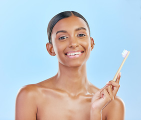 Image showing Toothbrush, portrait and a woman brushing teeth for dental health on a blue background for wellness. Happy indian female model with toothpaste and brush for a clean, fresh and healthy mouth in studio