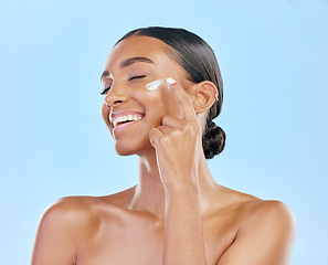 Image showing Face cream, skin and beauty of a happy woman with natural glow on a blue background. Dermatology, moisturizer and cosmetics of an Indian female model for facial shine, wellness or self care in studio