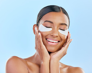 Image showing Beauty, eye patch and face of a woman with natural skin glow on a blue background. Dermatology, collagen mask and cosmetics of Indian female model for facial shine and touch for self care in studio