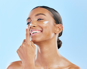 Image showing Beauty, face cream and skin of a happy woman with natural glow on a blue background. Dermatology, moisturizer and cosmetics of an Indian female model for facial shine, wellness or self care in studio