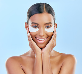 Image showing Beauty, skincare and portrait of woman with patches for eyes, dark circles and treatment. Smile, spa and Indian girl or model with a facial product for a glow isolated on a blue background in studio