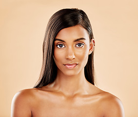 Image showing Face, skin and beauty portrait of a woman with natural glow on a beige background. Dermatology, makeup and cosmetics of serious Indian female model for facial shine, hair care or self love in studio