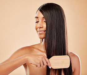 Image showing Face, hair beauty and brush with a woman in studio on a cream background for natural or luxury style. Haircare, growth and shampoo treatment with a young indian female model eyes closed at a salon