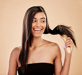 Image showing Smile, beauty and a woman brushing her hair in studio on a cream background for natural or luxury style. Haircare, face and shampoo with a happy young indian female model at the salon or hairdresser