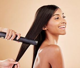 Image showing Flat iron, beauty and hair care of a woman in studio with hands of a stylist. Straightener, cosmetics and wellness of Indian person for hairdresser, hot tools or salon results on a beige background