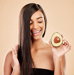 Image showing Smile, woman and avocado for hair care, beauty or cosmetic treatment of natural growth on studio background. Happy indian female model, green fruits and vegan dermatology for healthy keratin benefits