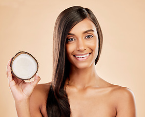 Image showing Portrait, woman and coconut for hair, beauty or cosmetic treatment for natural skincare on studio background. Happy indian female model with tropical fruits for hairstyle, aesthetic benefits or shine