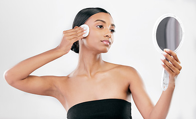 Image showing Woman, mirror and cotton pad for face, cosmetics and aesthetic skincare in studio on white background. Indian female model looking at reflection with beauty product for facial cleaning or dermatology