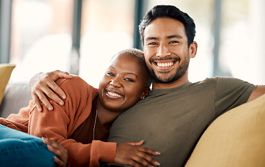 Image showing Happy hug, interracial couple and portrait on a sofa at home with love and care in a living room. Woman, young people and together in a house sitting on a lounge couch relax with support and embrace