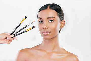 Image showing Portrait, woman and makeup brush set for face, cosmetics or aesthetic tools on white background in studio. Indian female model, facial beauty product or collection of foundation, skincare or makeover