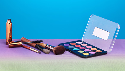 Image showing Makeup, product and palette for color in studio, brush and cosmetics for beauty, mock up and blue background. Powder, mascara and skincare with transformation, change and eyeshadow for aesthetic