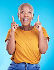 Image showing Excited, pointing up and happy black woman with studio advertising space, retail promotion news or announcement. Smile, brand notification and African person gesture at sales deal on blue background
