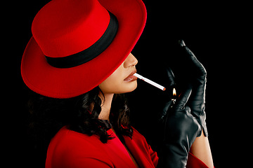 Image showing Vintage, style and a woman smoking a cigarette with retro fashion, style and aesthetic. 90s, mystery and a model or mafia girl with a smoke and fashionable isolated on a black background in a studio