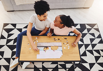 Image showing Puzzle, friends together and game in living room for fun, bonding or quality time of playing from above girls in house. Women, jigsaw and people happy to connect pieces on table in family home