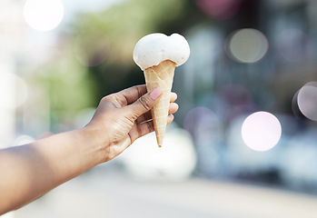 Image showing Hands, person and ice cream cone in city for dessert, cool snack and sweet food to enjoy outdoor. Closeup, scoop and frozen vanilla gelato in summer, travel and sunshine of urban town, street or trip