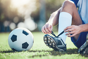 Image showing Ball, man and soccer player tie shoes for training, fitness games and performance on field. Closeup, football athlete and lace sneakers on feet, grass pitch and sports competition on stadium ground