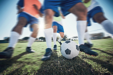 Image showing Football player, feet and men with a ball together on a field for sports game or fitness. Blurred closeup of male soccer team or athlete group for tackle challenge, action or training workout outdoor