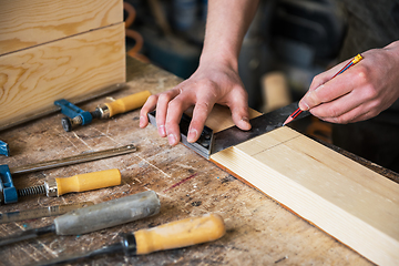 Image showing The worker makes measurements of a wooden board