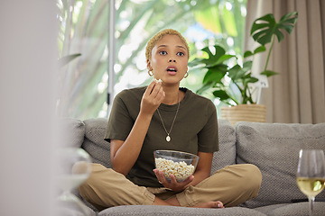 Image showing Surprise, watching tv and a woman on the sofa with popcorn for a movie or show. Wow, house and a young girl eating a snack while on the living room couch for a horror, film or streaming a drama