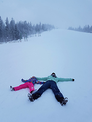 Image showing Daughter and mother are playing and lying in the snow in winter 