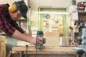 Image showing Worker grinds the wood box