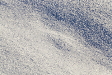 Image showing land covered with snow - white snow after snow had fallen and covered the land in the agricultural field. Photo closeup in the winter season, a small depth of field. On visible surface roughness snow