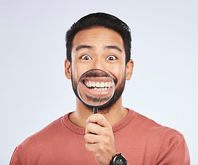 Image showing Magnifying glass, mouth and portrait of a man with a smile for teeth, beauty or dental hygiene. Happy, healthy and an Asian person or model with gear to show oral care results on a white background