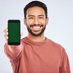 Image showing Phone, green screen and portrait of asian man with mockup for app, menu or checklist on grey background. Space, display and face of male person with smartphone platform for social media or networking