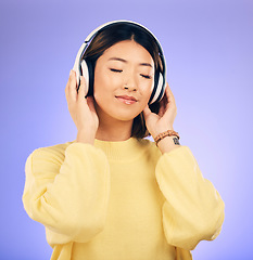 Image showing Headphones, music and happy Asian woman relax in studio for streaming app, subscription and radio. Calm, podcast and isolated female person listening to audio, song and track on purple background