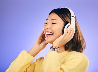 Image showing Happy asian woman, headphones and listening to music for online streaming against a purple studio background. Female person or model smile enjoying audio track, sound or songs on headset on mockup