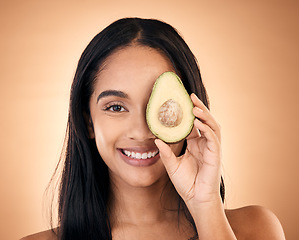 Image showing Happy, face and woman with avocado for skincare isolated on a brown background in studio. Portrait, fruit and model with food for nutrition, skin health and vegan diet, omega 3 or natural cosmetics